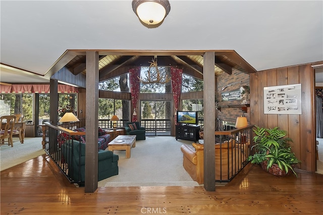 interior space with a healthy amount of sunlight, beam ceiling, wood finished floors, and wooden walls