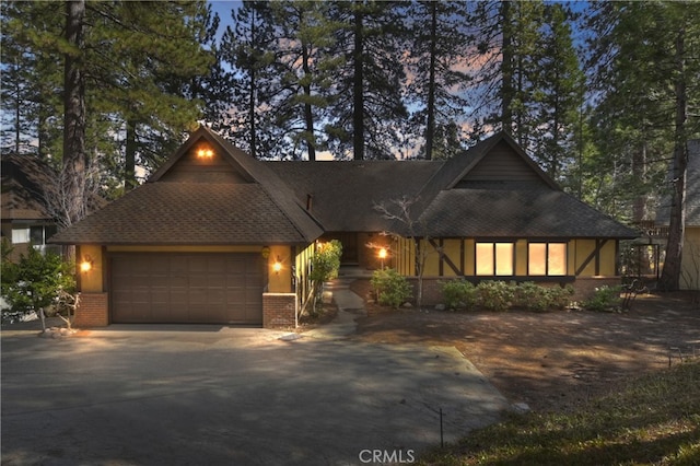 view of front of property featuring brick siding, driveway, and a garage