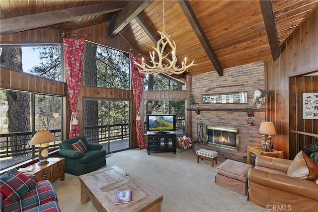 unfurnished living room with wood walls, light carpet, a brick fireplace, a notable chandelier, and beam ceiling