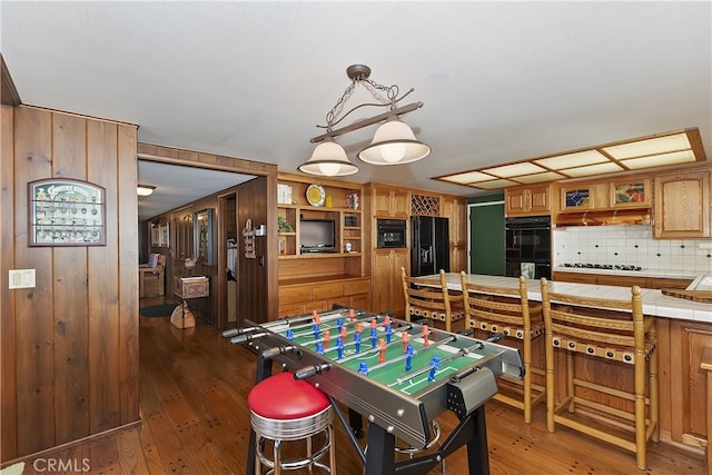 game room with dark wood finished floors and wooden walls