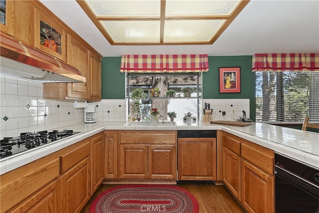 kitchen with decorative backsplash, brown cabinets, white gas cooktop, dark wood finished floors, and tile counters