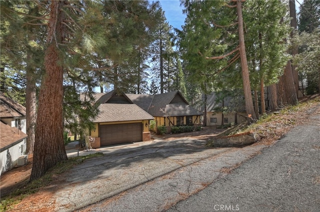 chalet / cabin featuring brick siding, driveway, and a garage