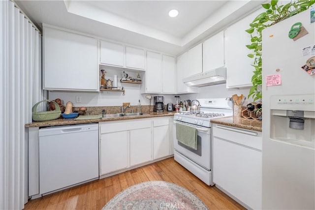 kitchen featuring white appliances, light wood finished floors, under cabinet range hood, white cabinetry, and a sink