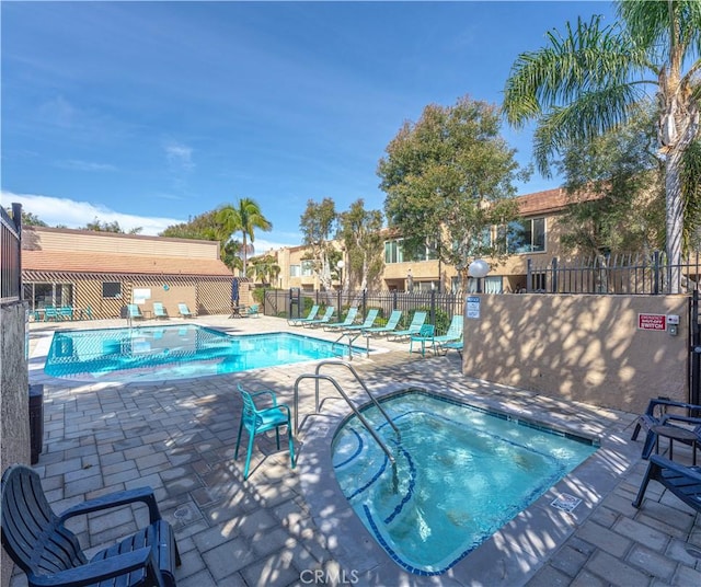 pool with a community hot tub, a patio, and fence