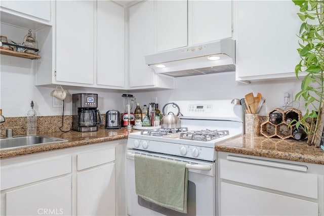 kitchen featuring white gas stove, stone counters, under cabinet range hood, a sink, and white cabinets