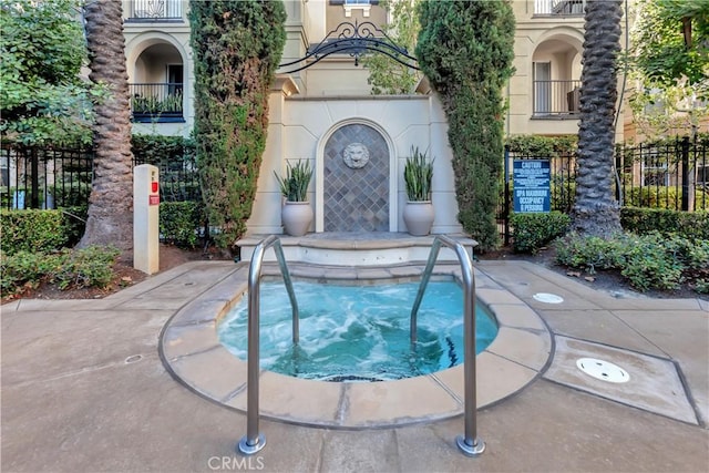 view of pool featuring fence and a hot tub