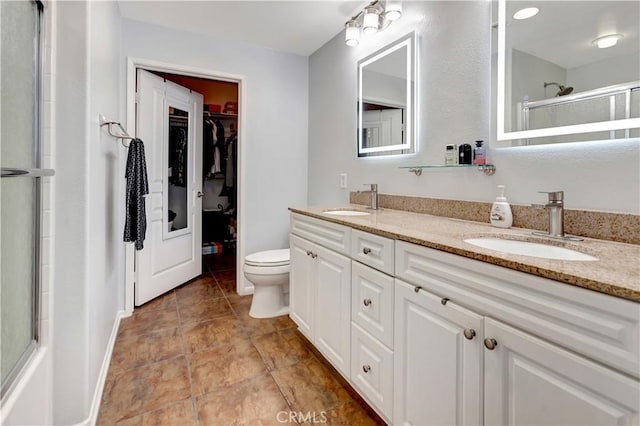 full bath featuring double vanity, a sink, a walk in closet, and a shower with door