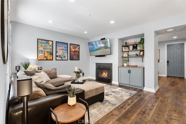 living room with a glass covered fireplace, dark wood finished floors, baseboards, and recessed lighting