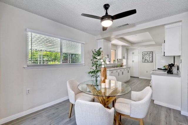 dining space with sink, a textured ceiling, and light hardwood / wood-style floors