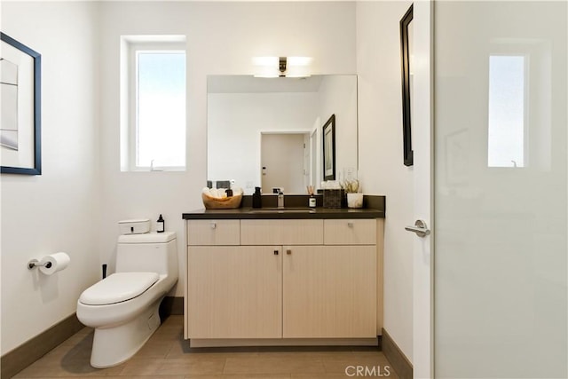 bathroom with toilet, baseboards, and vanity