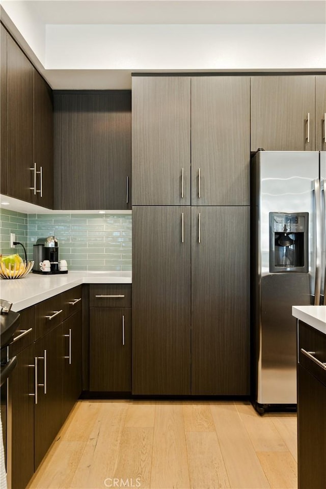 kitchen with light wood finished floors, tasteful backsplash, light countertops, dark brown cabinets, and stainless steel fridge with ice dispenser