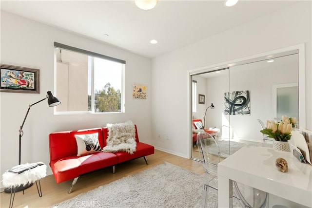 living area featuring baseboards, light wood finished floors, and recessed lighting