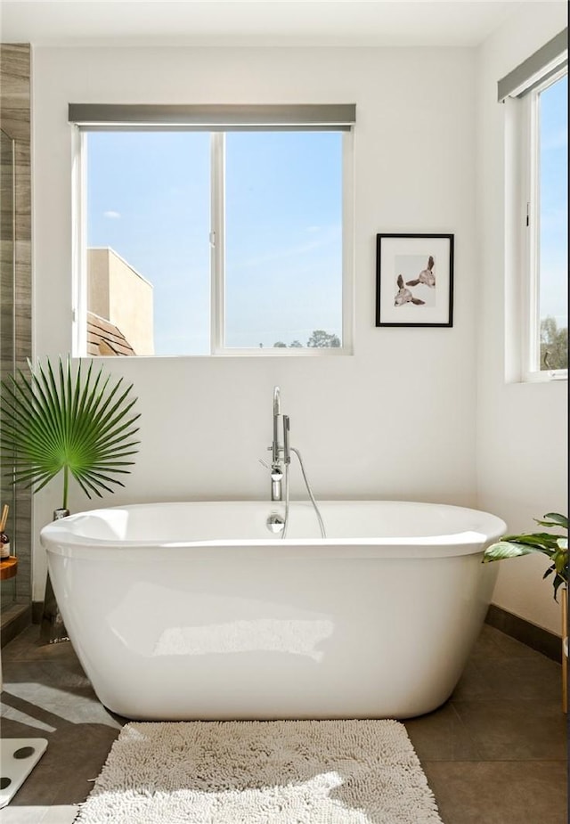 full bath with tile patterned flooring, a soaking tub, and baseboards