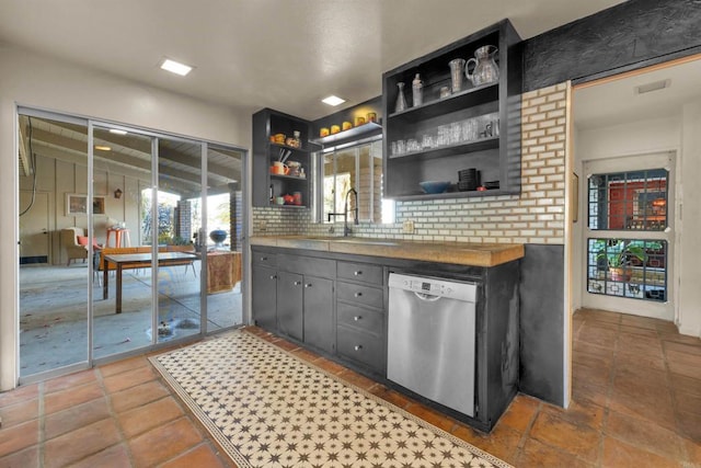 kitchen featuring stainless steel dishwasher, decorative backsplash, sink, and butcher block counters