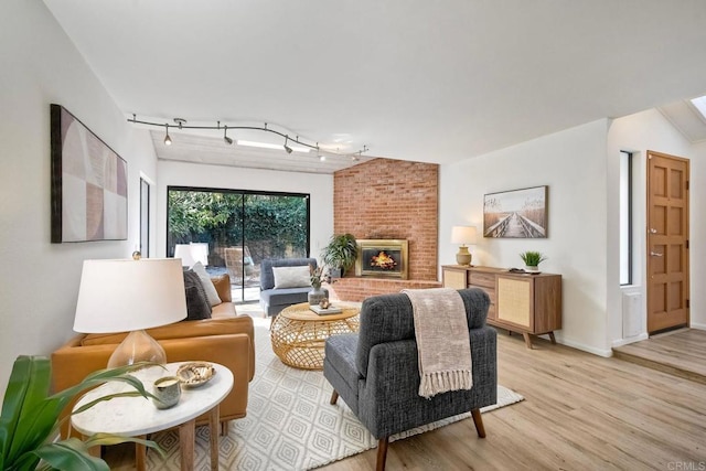 living room with a fireplace, baseboards, track lighting, and wood finished floors