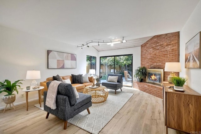 living area with light wood finished floors, a fireplace, baseboards, and track lighting