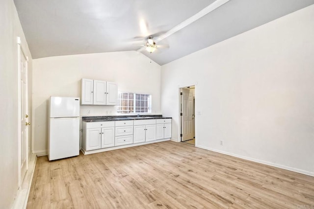 kitchen featuring white cabinetry, dark countertops, freestanding refrigerator, and light wood-style floors