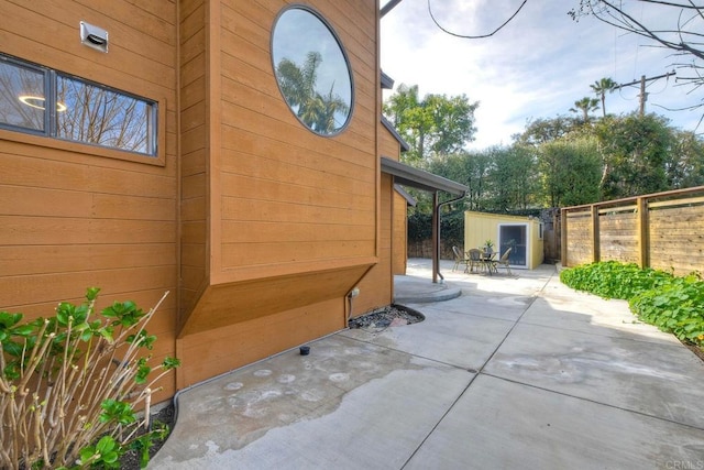 view of home's exterior with fence private yard, a patio area, a storage unit, and an outdoor structure