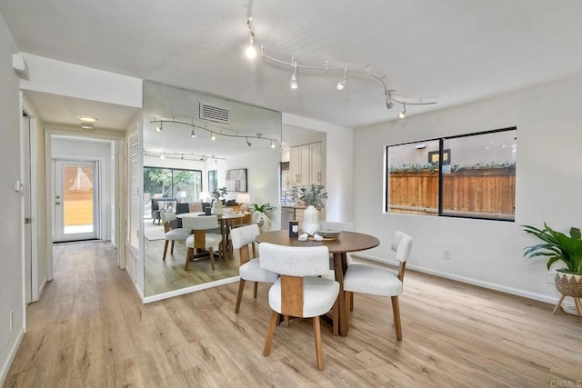 dining room with track lighting, light wood-type flooring, visible vents, and baseboards