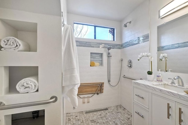 bathroom with tiled shower and vanity