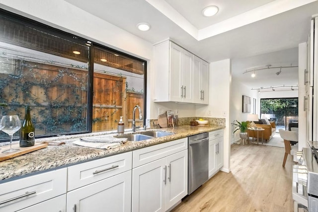 kitchen featuring light stone counters, white cabinetry, a sink, light wood-type flooring, and dishwasher