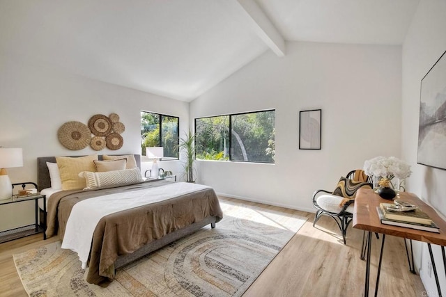 bedroom with lofted ceiling with beams, baseboards, and light wood-style floors