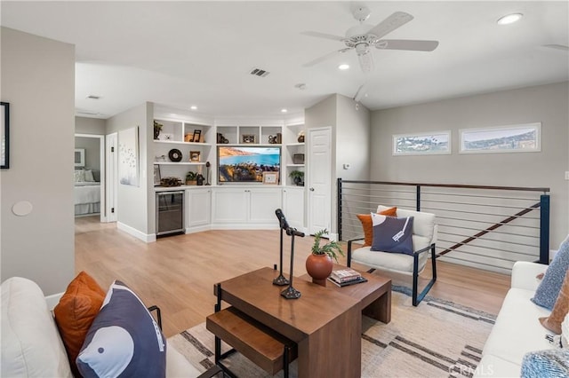 living area featuring recessed lighting, beverage cooler, visible vents, baseboards, and light wood finished floors