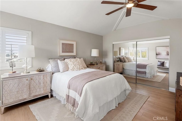 bedroom featuring lofted ceiling, ceiling fan, a closet, and light wood-style floors