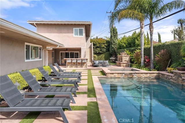 view of swimming pool with a fenced in pool, exterior bar, a jacuzzi, a patio area, and an outdoor living space with a fireplace