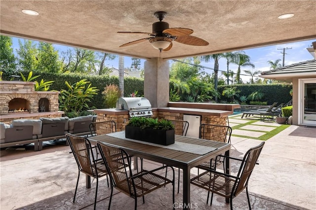 view of patio featuring an outdoor kitchen, a ceiling fan, grilling area, outdoor dining area, and an outdoor stone fireplace