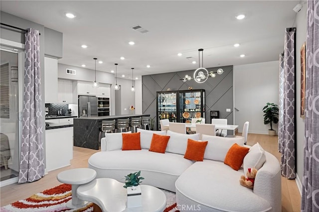 living area featuring light wood-type flooring, visible vents, and recessed lighting