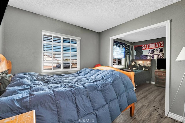 bedroom featuring a textured ceiling, wood finished floors, and multiple windows