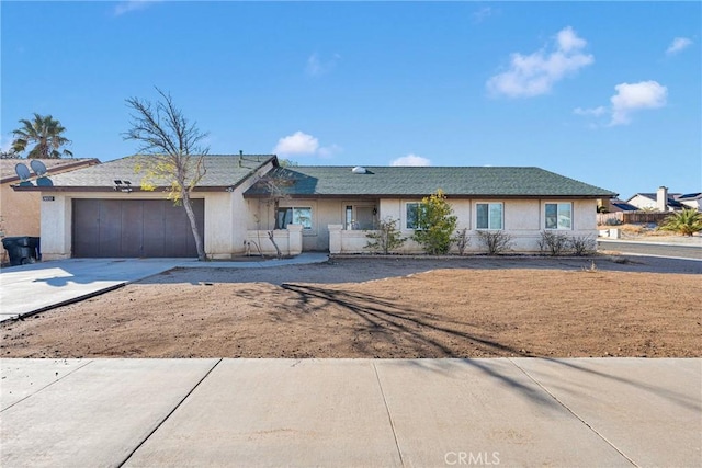 ranch-style home with stucco siding, an attached garage, and driveway