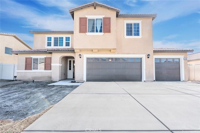 mediterranean / spanish home with fence, driveway, stucco siding, a garage, and a tiled roof