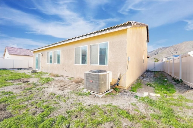 rear view of house featuring central AC unit, a fenced backyard, and stucco siding