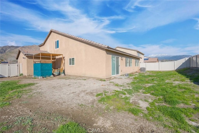 back of house with a tiled roof, stucco siding, cooling unit, and a fenced backyard