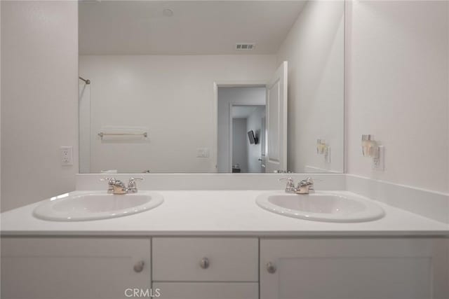 bathroom with a sink, visible vents, and double vanity