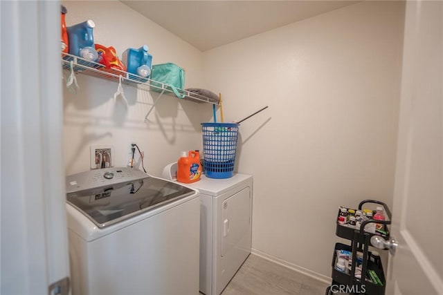 laundry room featuring laundry area, independent washer and dryer, light wood-style flooring, and baseboards