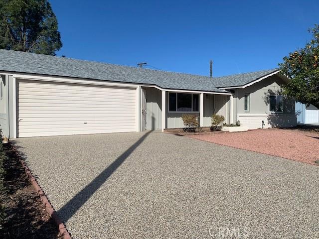 single story home featuring roof with shingles, gravel driveway, and an attached garage