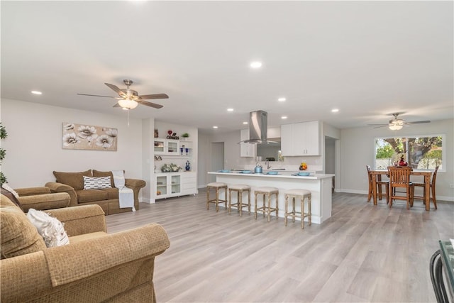 living room featuring baseboards, a ceiling fan, recessed lighting, and light wood-type flooring