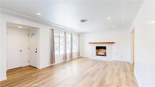 unfurnished living room featuring light wood-style flooring, visible vents, a fireplace with flush hearth, and recessed lighting