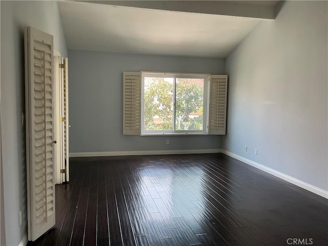 spare room with lofted ceiling, baseboards, and dark wood-style flooring