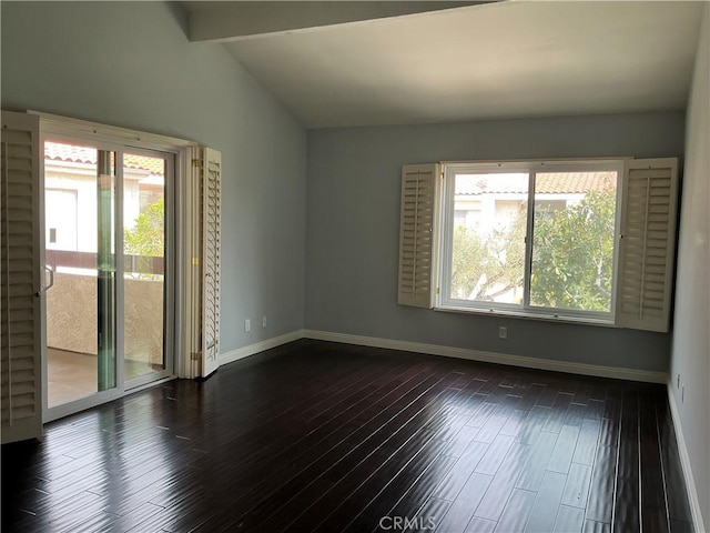 empty room with dark wood finished floors, lofted ceiling with beams, a healthy amount of sunlight, and baseboards