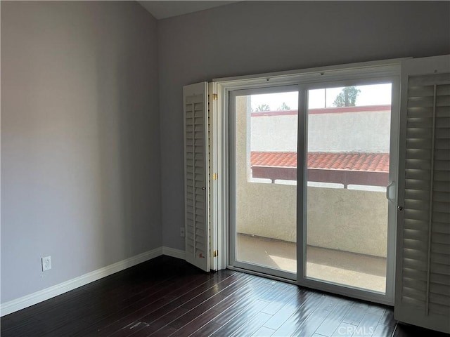 empty room featuring baseboards and dark wood-style flooring