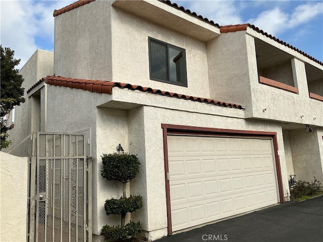 view of front of house featuring stucco siding, a tiled roof, and a garage