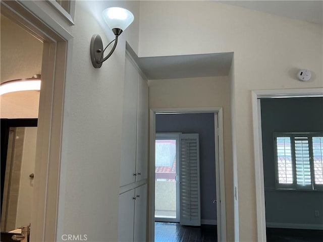 corridor featuring dark wood-type flooring and baseboards