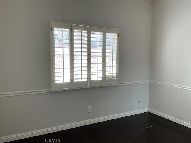 spare room featuring dark wood-style floors and baseboards