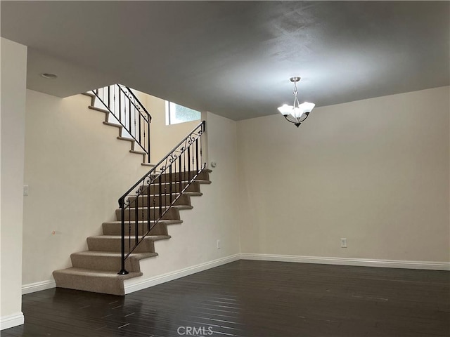 stairway with baseboards, an inviting chandelier, and wood finished floors