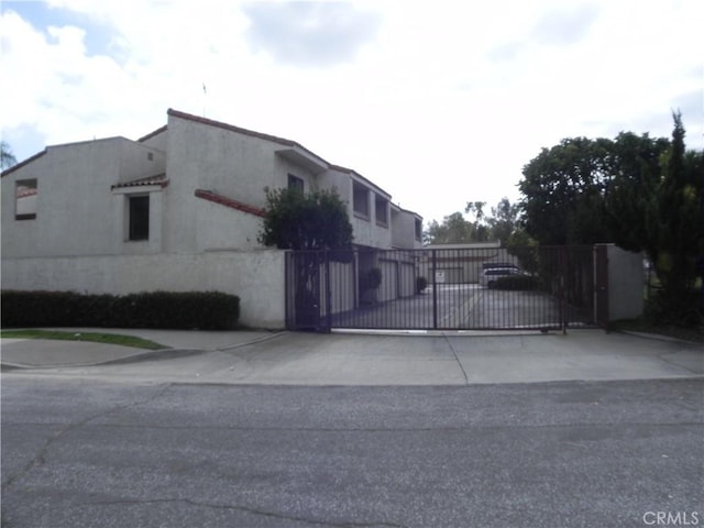 view of property exterior featuring stucco siding, fence, and a gate