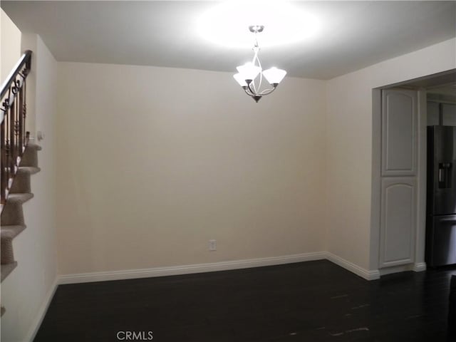 unfurnished room with baseboards, an inviting chandelier, dark wood finished floors, and stairs